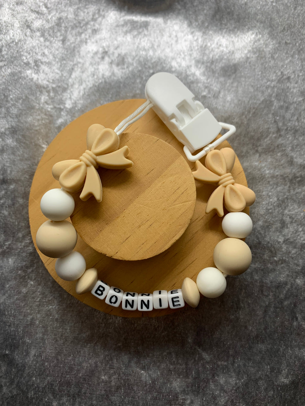 Dummy clip white and beige beads, and 'Bonnie' label on a gray background