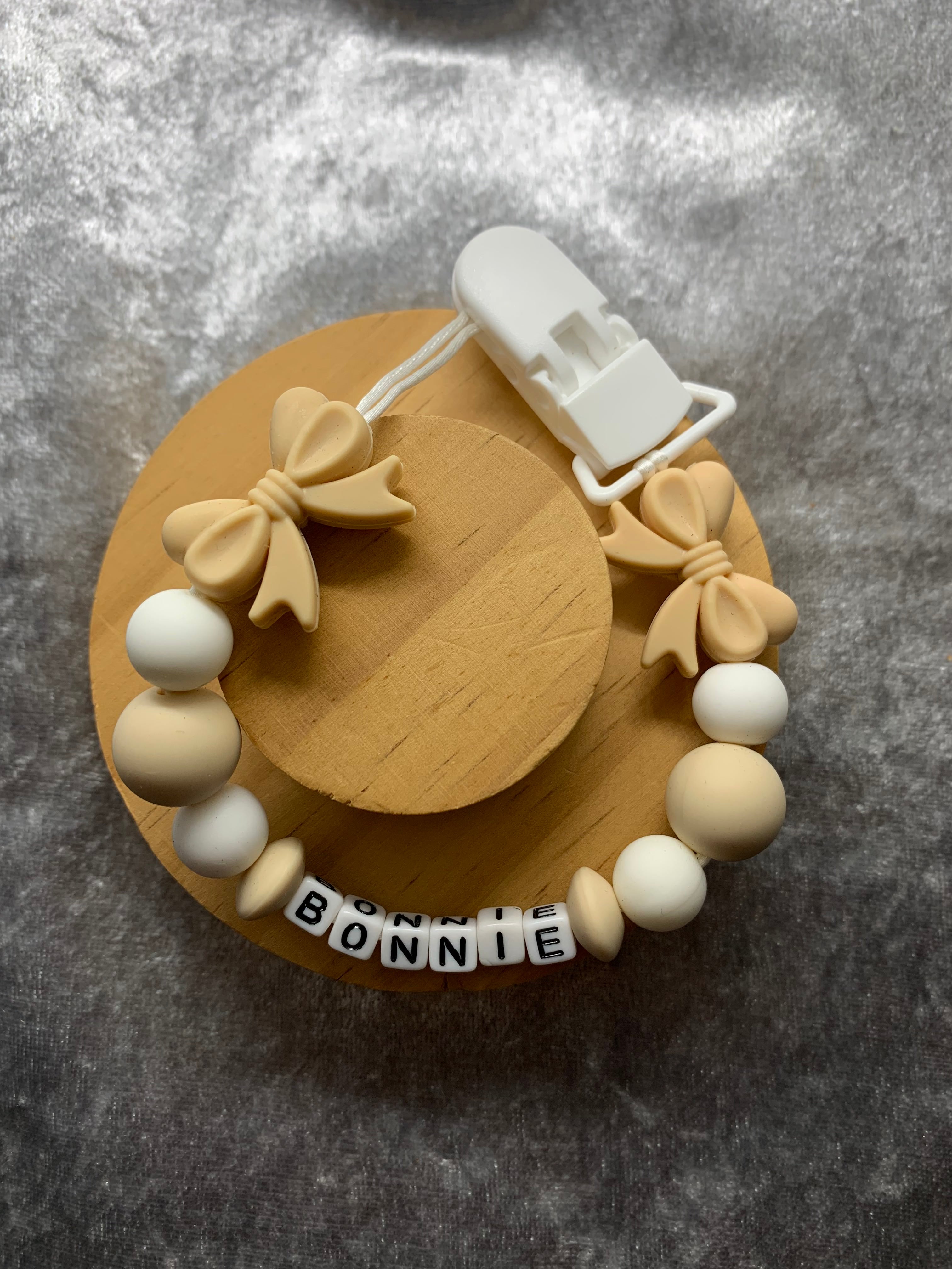 Dummy clip white and beige beads, and 'Bonnie' label on a gray background