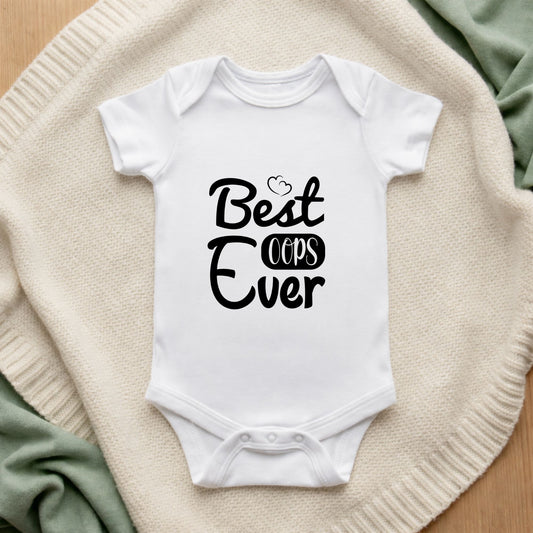 White baby onesie with 'Best Oops Ever' text on a textured surface