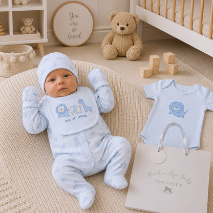 Newborn baby in blue outfit with lion design, surrounded by baby items in a nursery.