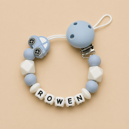 Silicone dummy clip with car design and letter beads spelling 'ROWEN' on a beige background