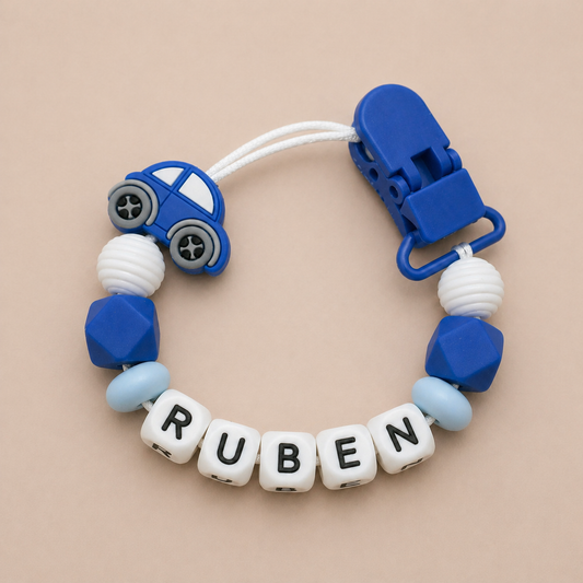 dummy clip with blue car design, white beads spelling 'RUBEN', and blue clip on beige background