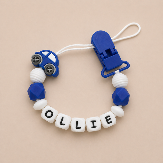 Silicone teether with blue car design and 'OLLIE' beads on a beige background