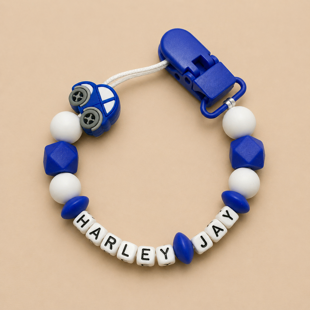 Blue and white dummy clip with 'Harley Jay' on a beige background