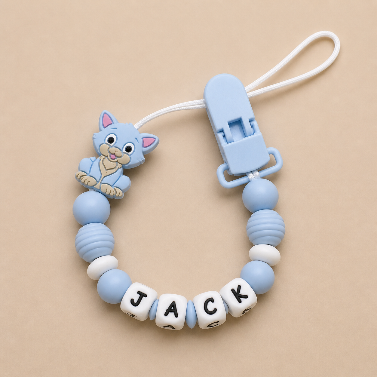Baby dummy clip with blue and white beads and a cat charm on a beige background