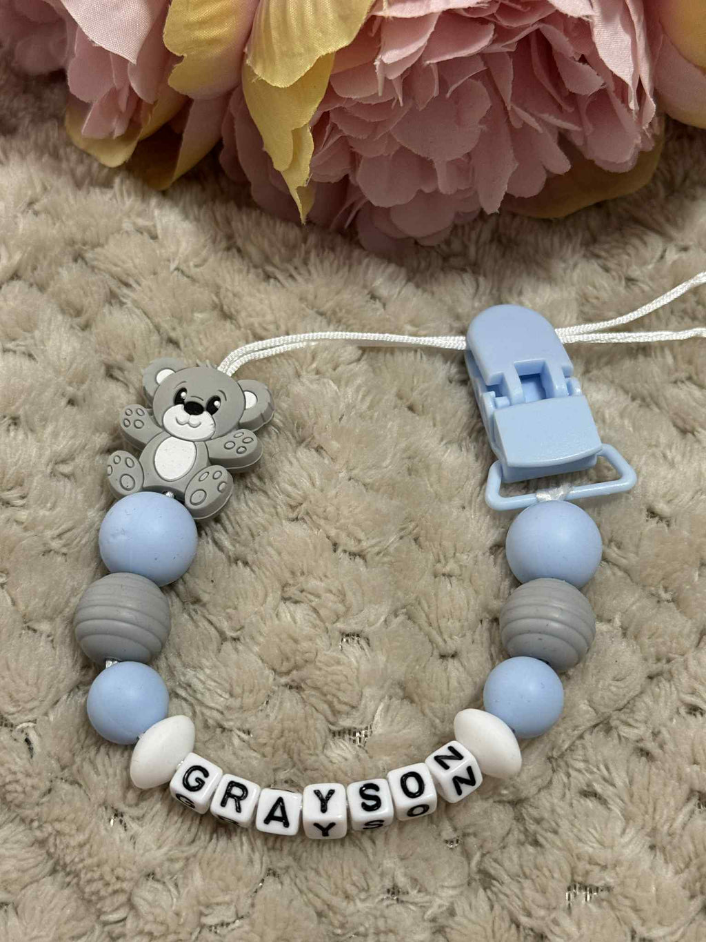 Blue, White and Grey teddybear dummy chain on a beige textured surface personalised with the name 'Grayson'. Personalisation and MAM Adapter options available.