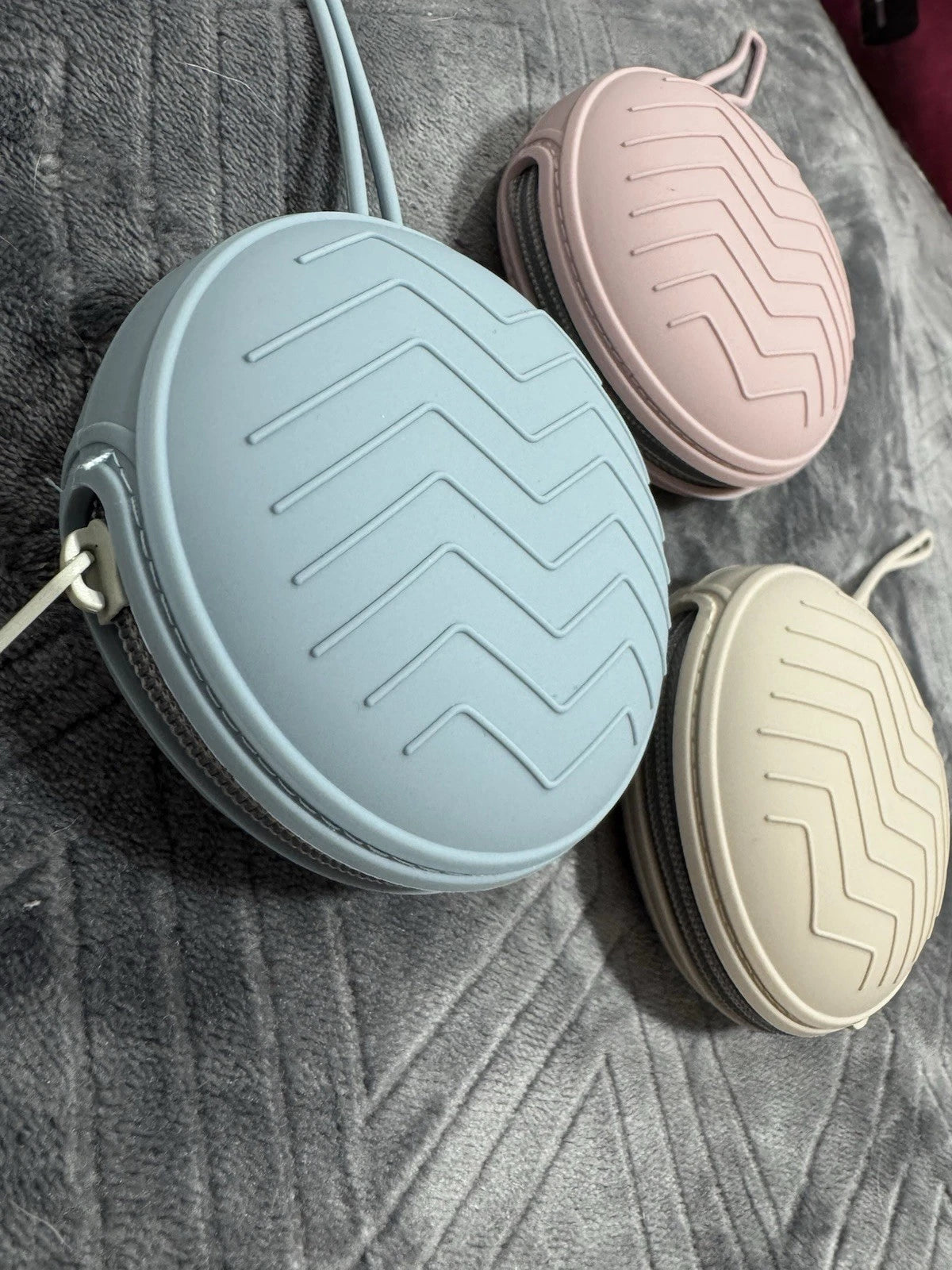 Blue, Pink and cream silicone cases for dummy clips on a grey textured surface.