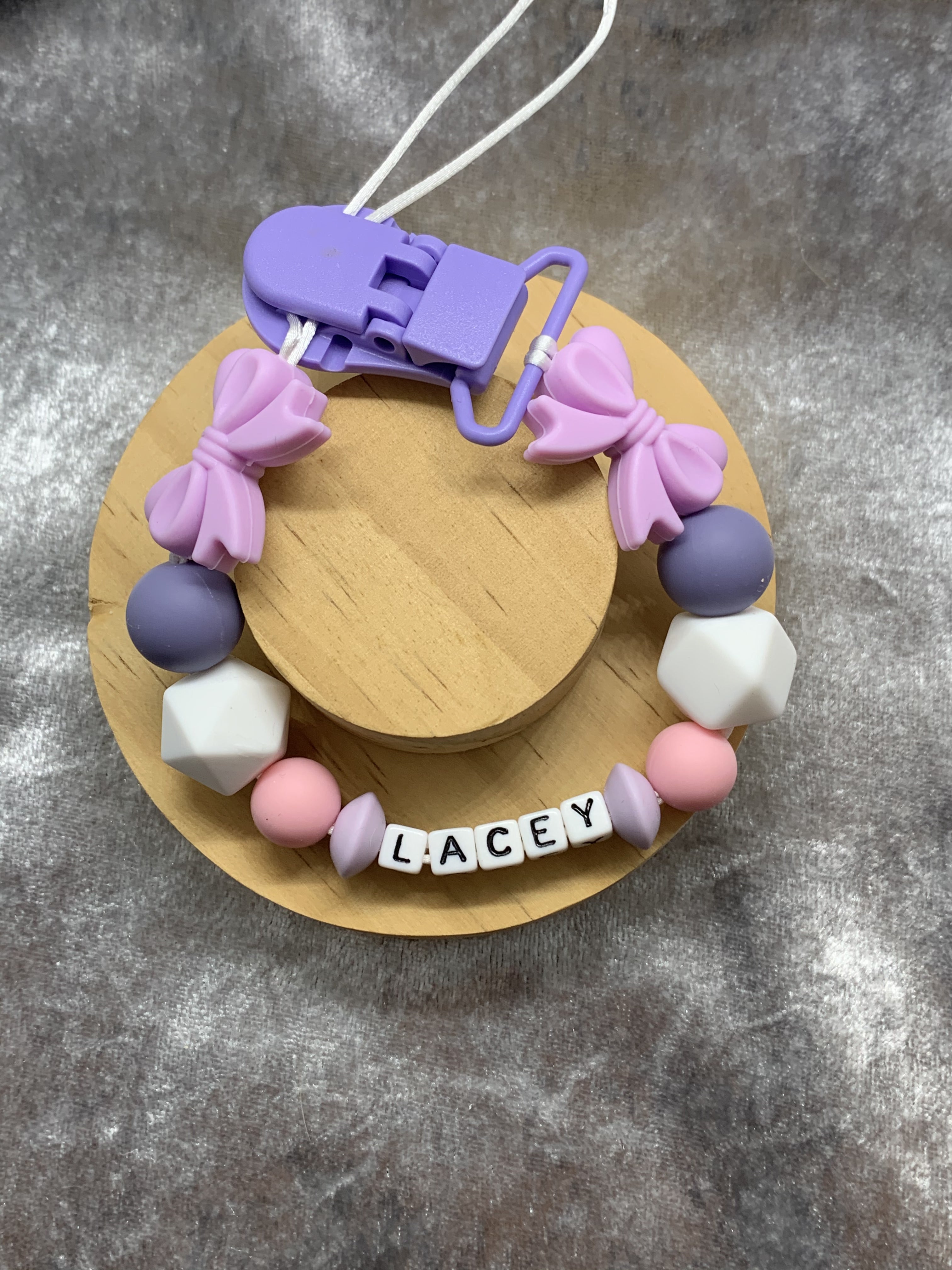 Colorful dummy chain with silicone beads and a wooden base on a gray surface