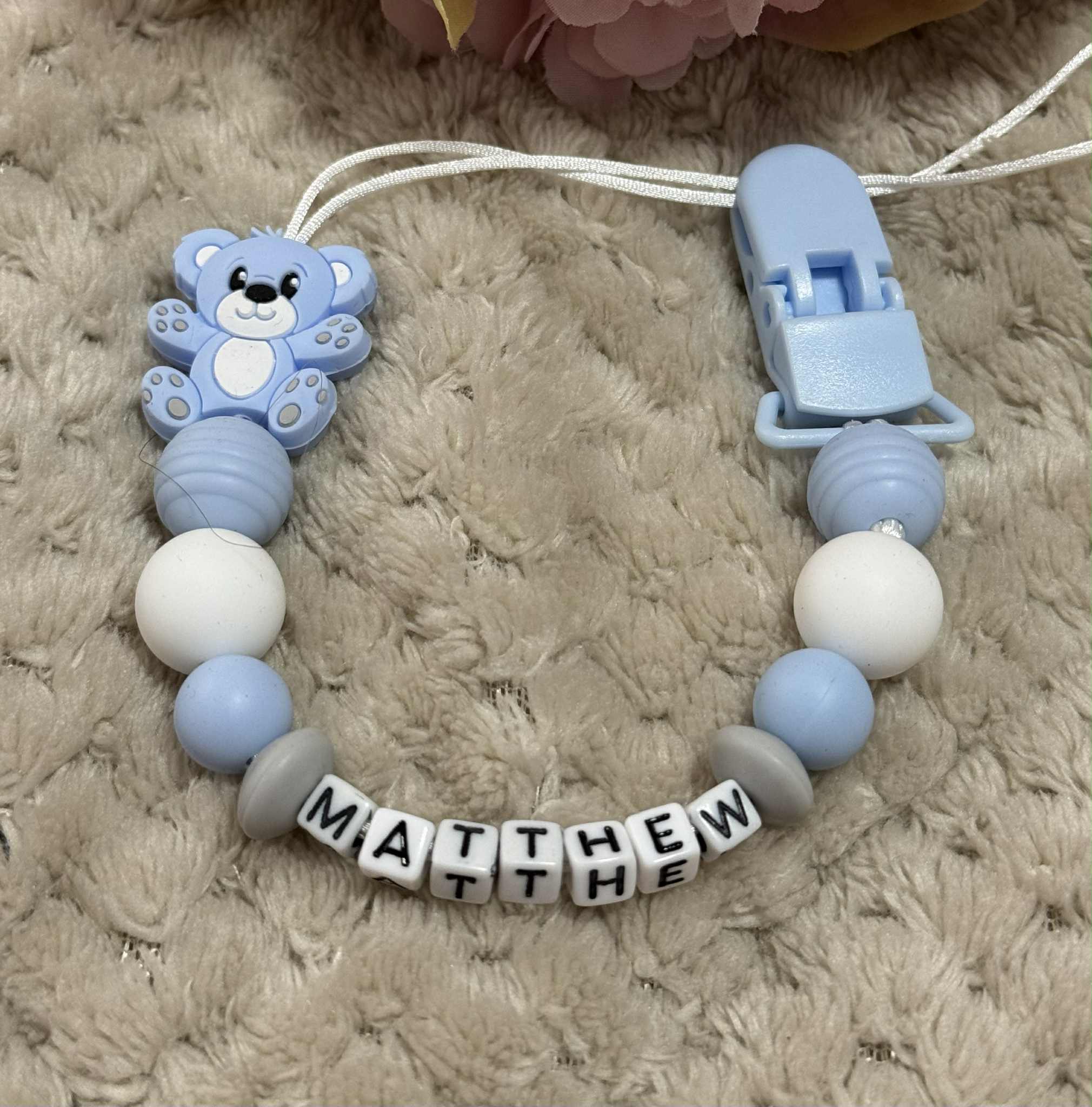 Blue, Grey and white teddybear dummy chain on a beige textured surface personalised with the name ''Matthew'. Personalisation and MAM Adapter options available.