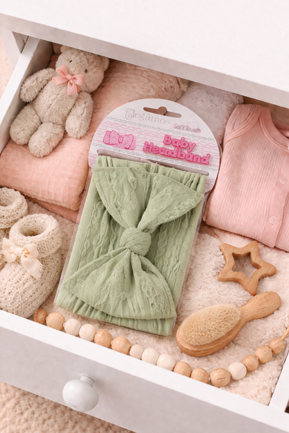 Baby items including a green headband, pink clothes, and wooden toys in a white drawer.