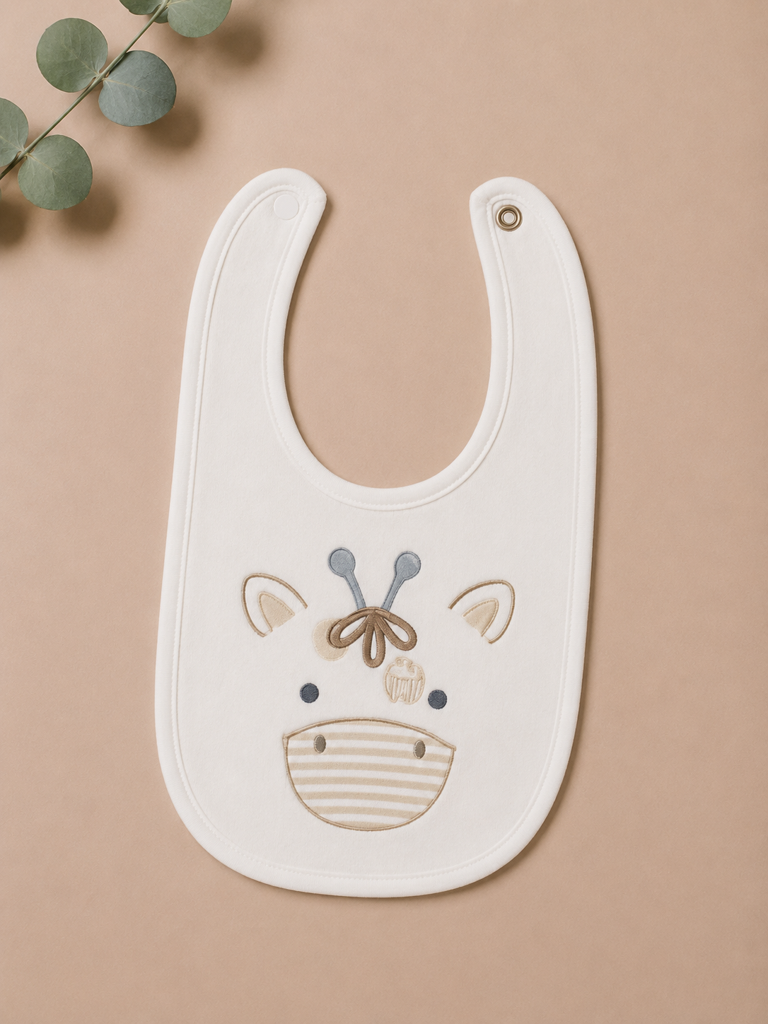 White bib with a giraffe design on a beige background