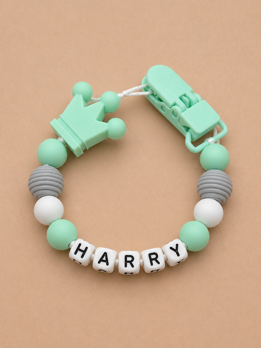 Teething bracelet with colorful beads and letter cubes spelling 'HARRY' on a beige background