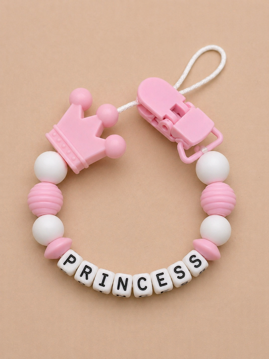Pink and white teething ring with 'PRINCESS' letter beads on a beige background