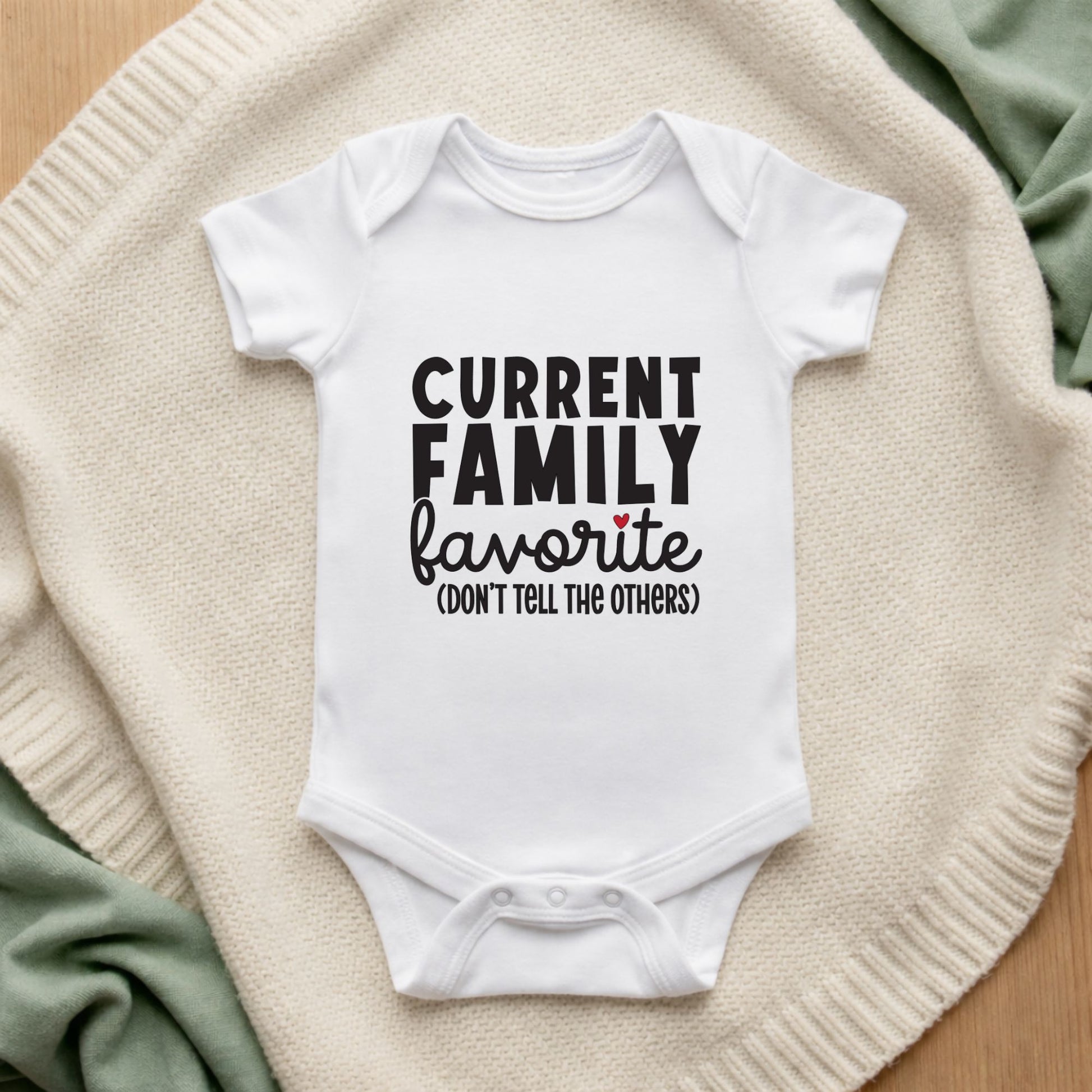 White baby onesie with text on a textured surface Current Family Favourite Baby Bodysuit