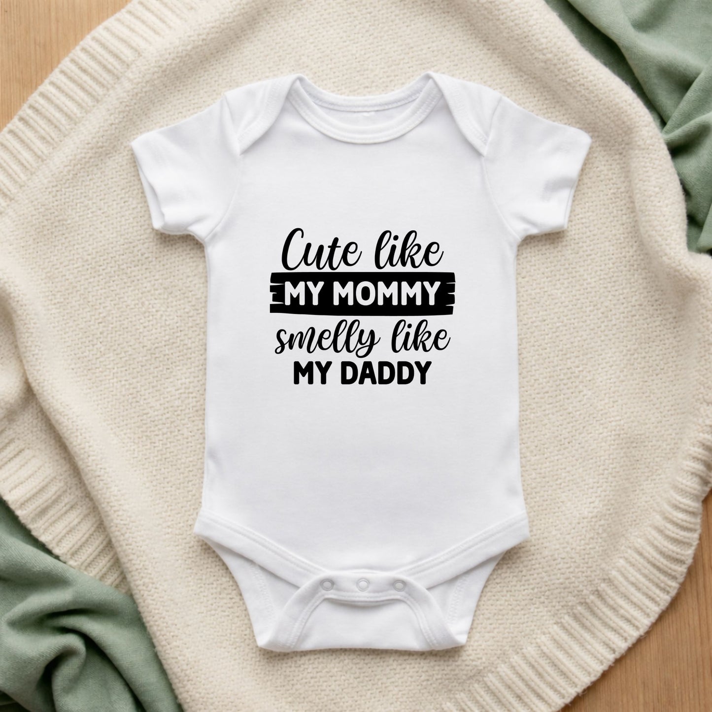 White baby onesie with text on a textured surface