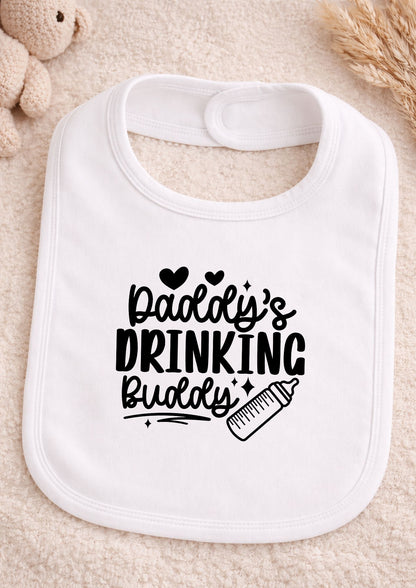 White baby bib with black text 'Daddy's Drinking Buddy' on a beige surface.