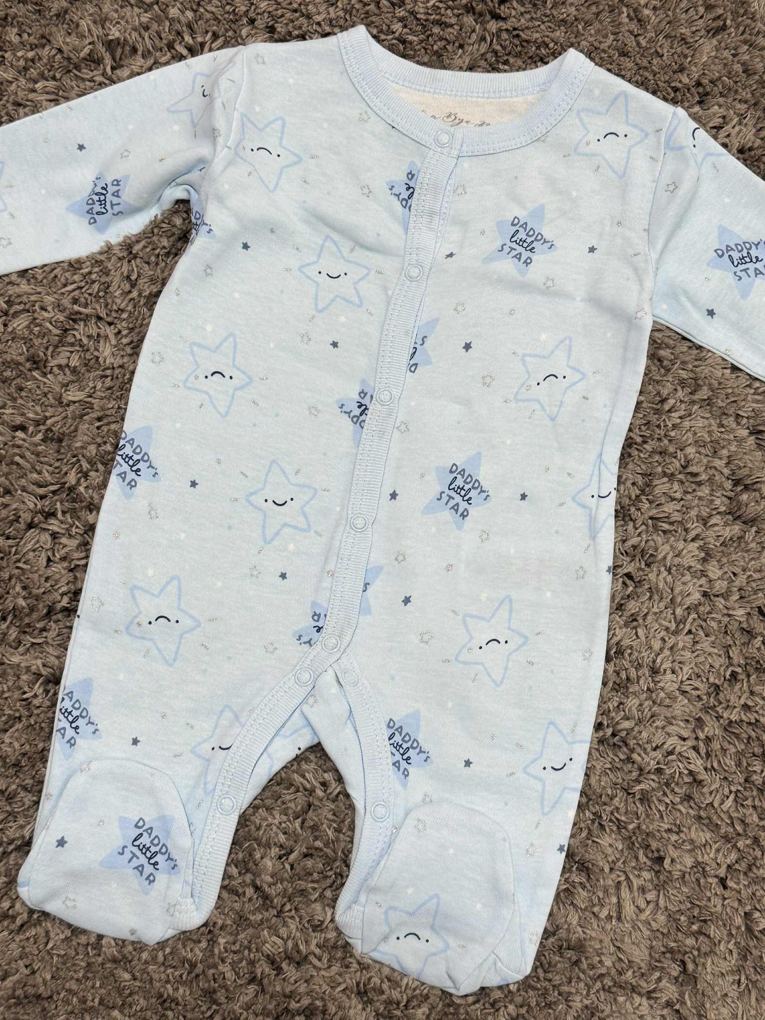 Baby onesie with star pattern on a brown carpet