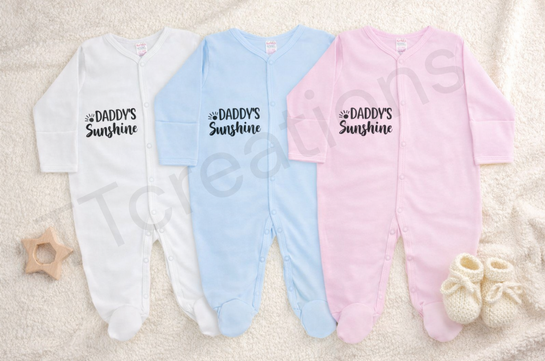 white, blue, and pink baby sleepsuits with the text “Daddy’s Sunshine” displayed on a neutral background.