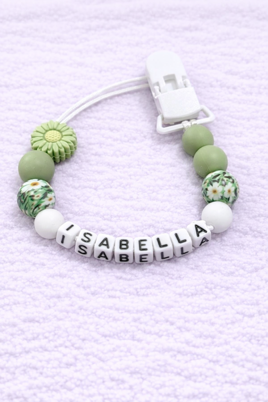 Dummy Chain with green beads and a name tag on a light purple textured background