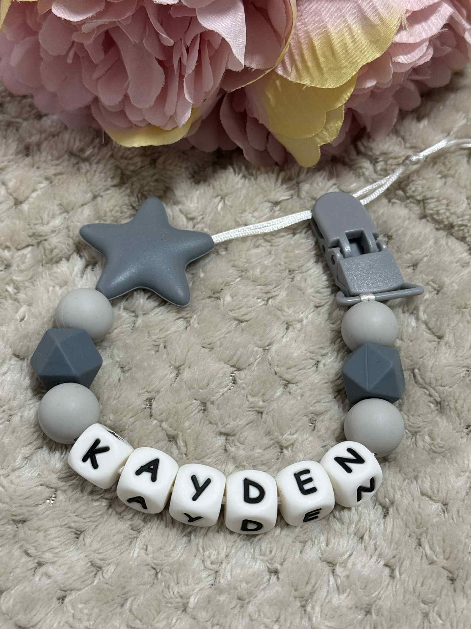 A dummy clip in Light And Dark Grey colors, personalized with any name 