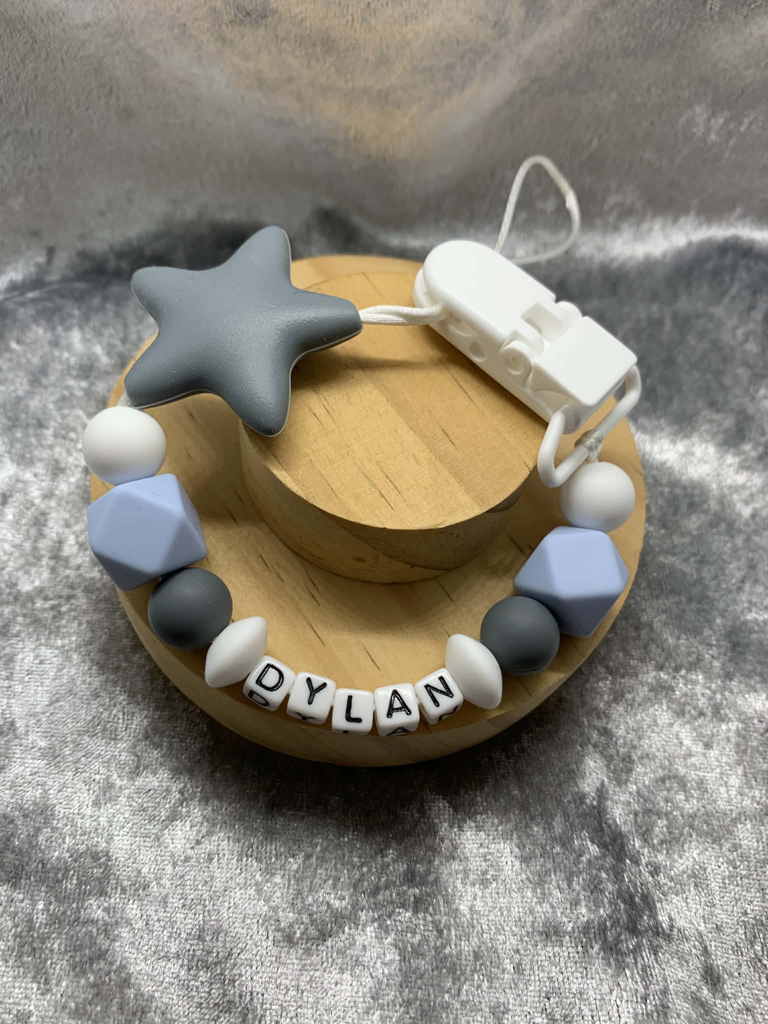 Dark Grey, Blue and white star personalised with the name 'Dylan' on a grey textured surface. Can be personalised