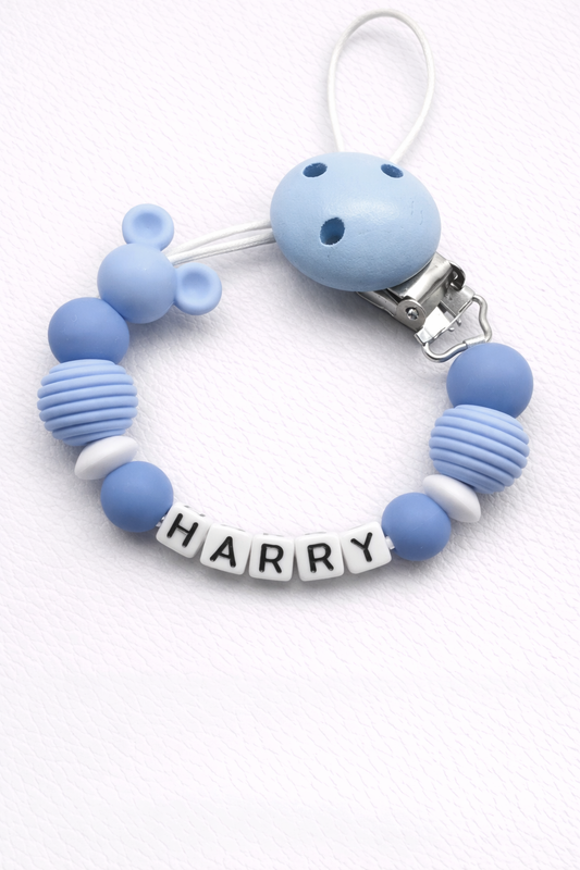 Blue silicone dummy clip with a clip and 'HARRY' name tag on a white background