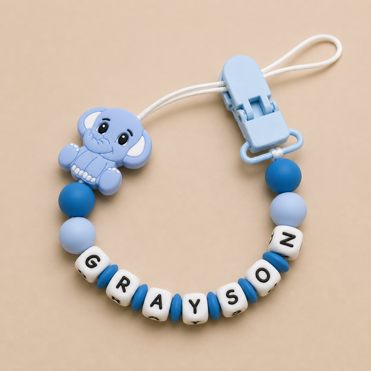 Blue elephant-shaped teether with letter beads on a beige background