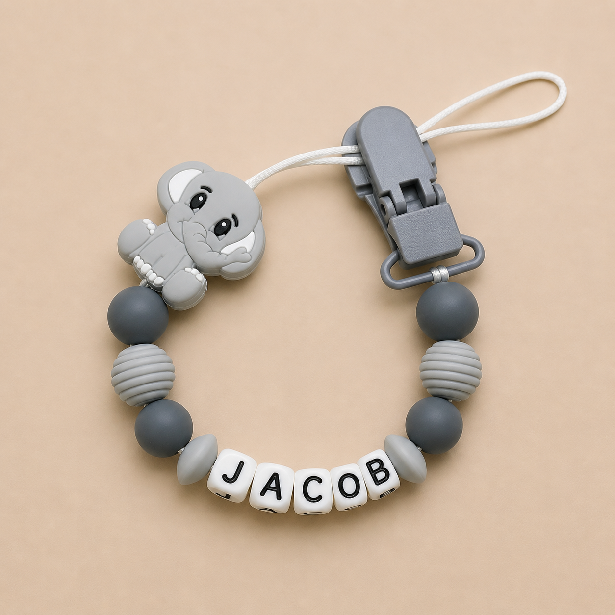 Silicone dummy clip with gray monkey design and 'JACOB' name on a beige background