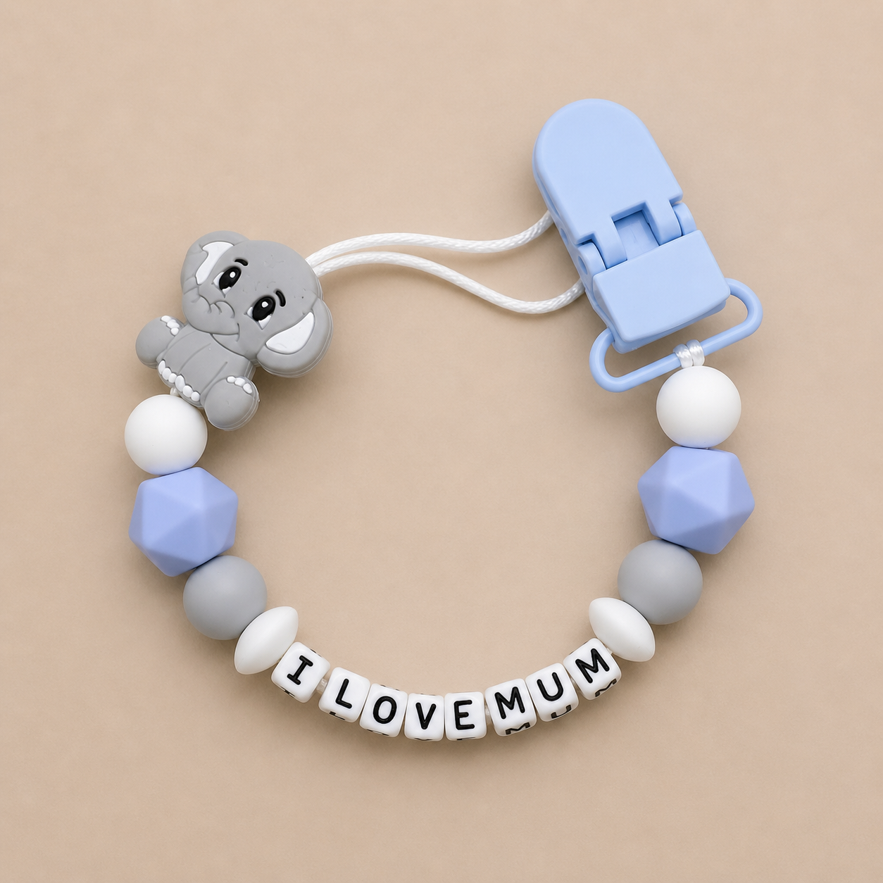 dummy clip with elephant charm, letter beads, and clip on beige background