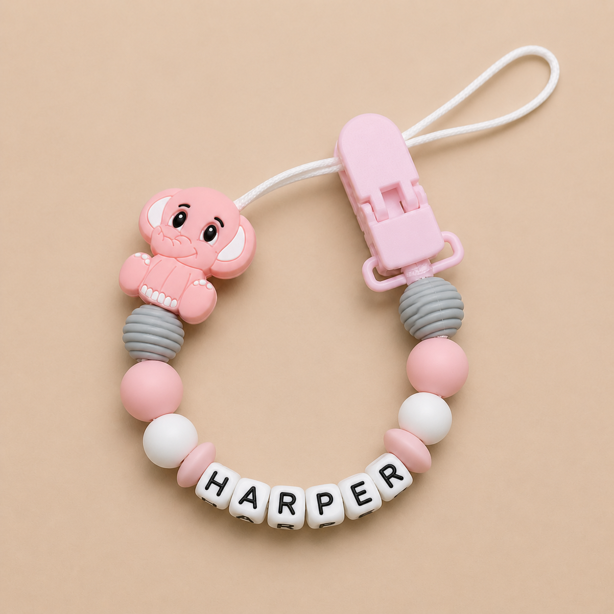 Pink and gray dummy clip with 'Harper' on a beige background
