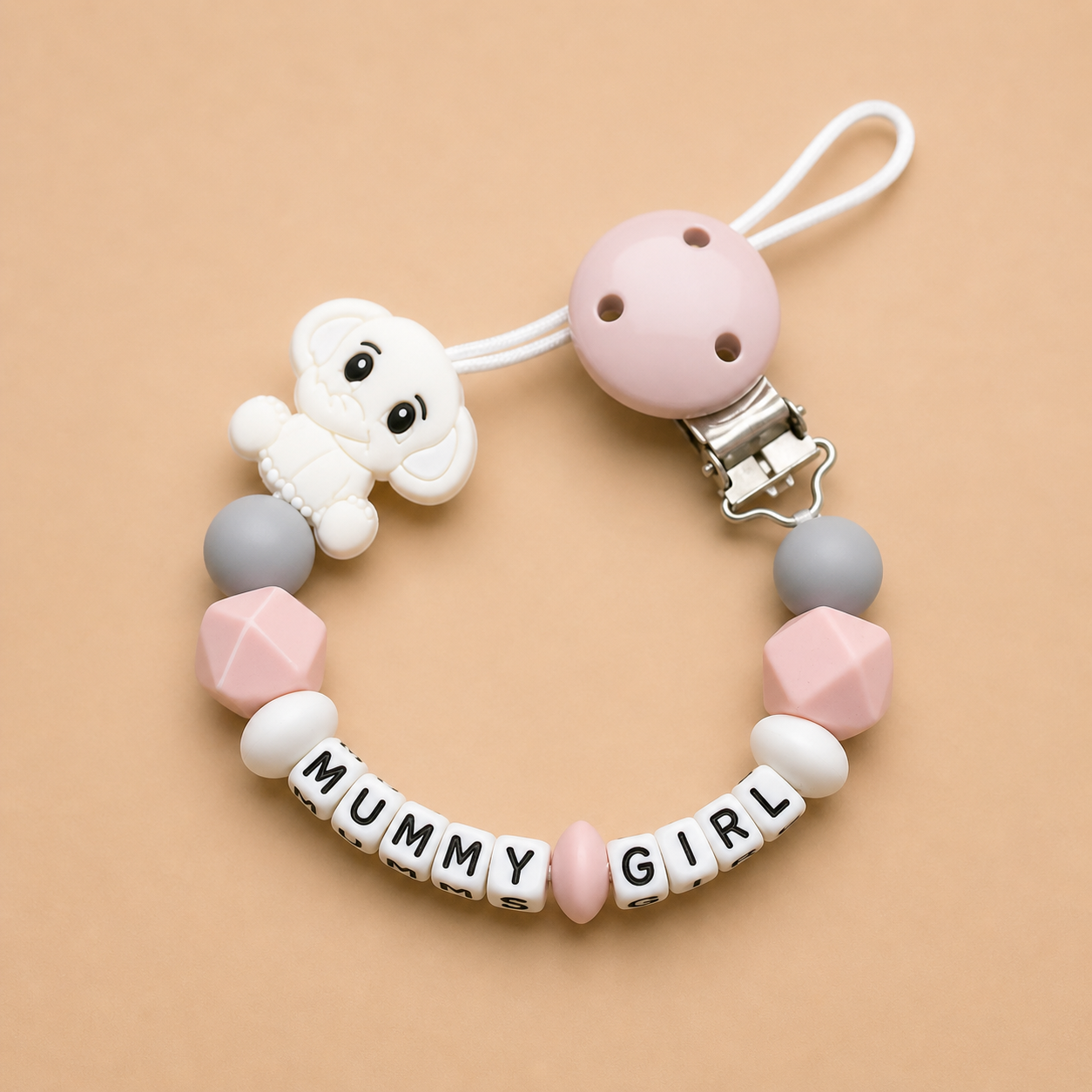 Baby teether with 'MUMMY GIRL' beads on a beige background