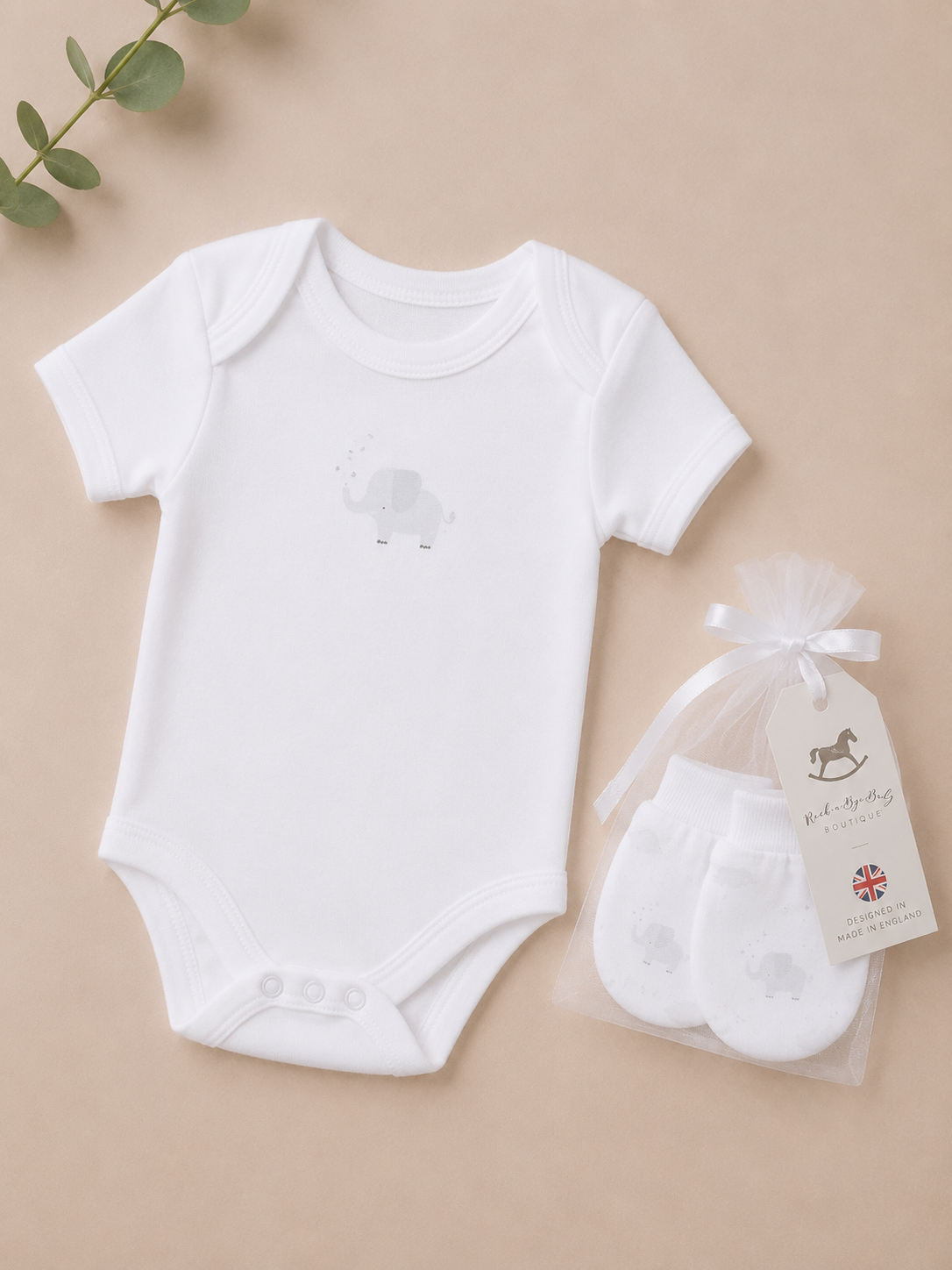 White baby bodysuit and white baby socks with a tag on a beige background