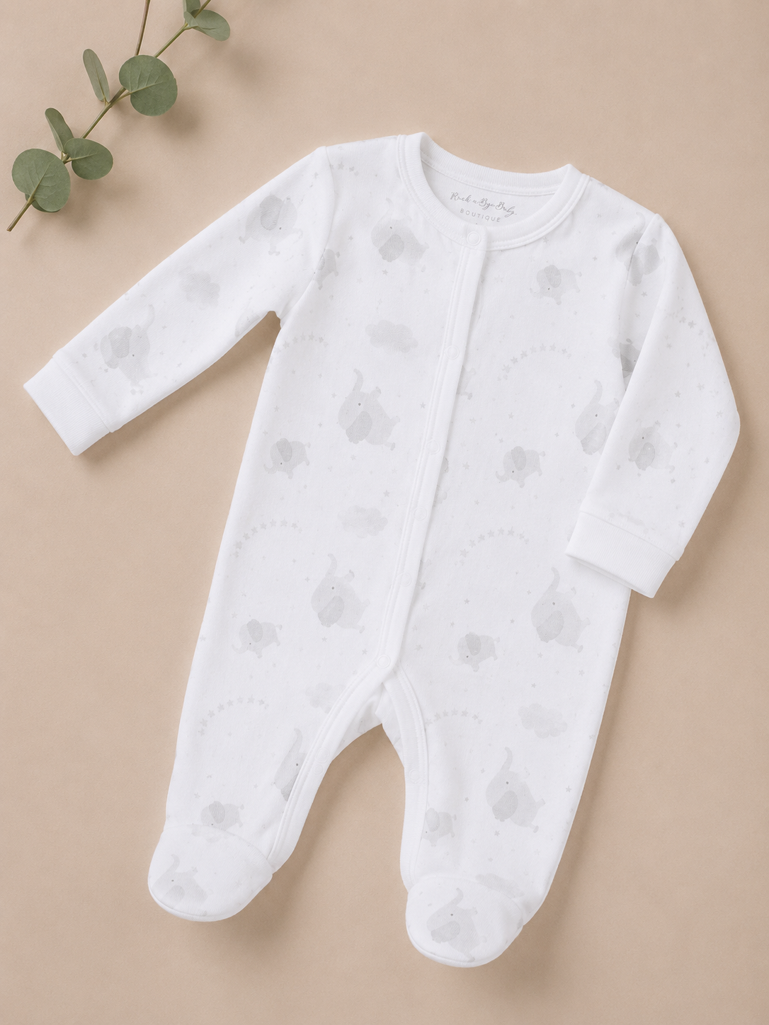 White baby onesie with footies on a beige background
