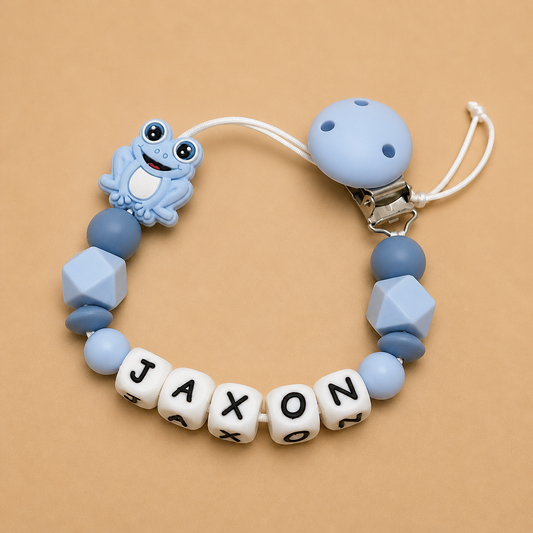 Silicone dummy clip with 'JAXON' beads on a beige background