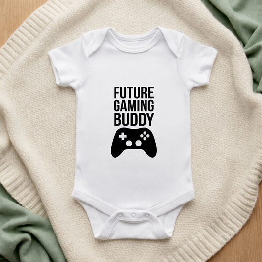 White baby onesie with 'Future Gaming Buddy' text and game controller graphic on a textured surface.