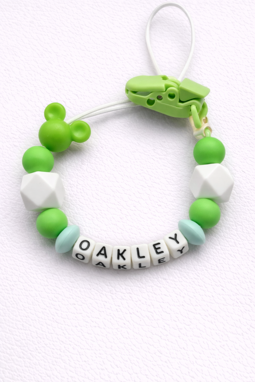 Green and white dummy clip with 'OAKLEY' on a white background