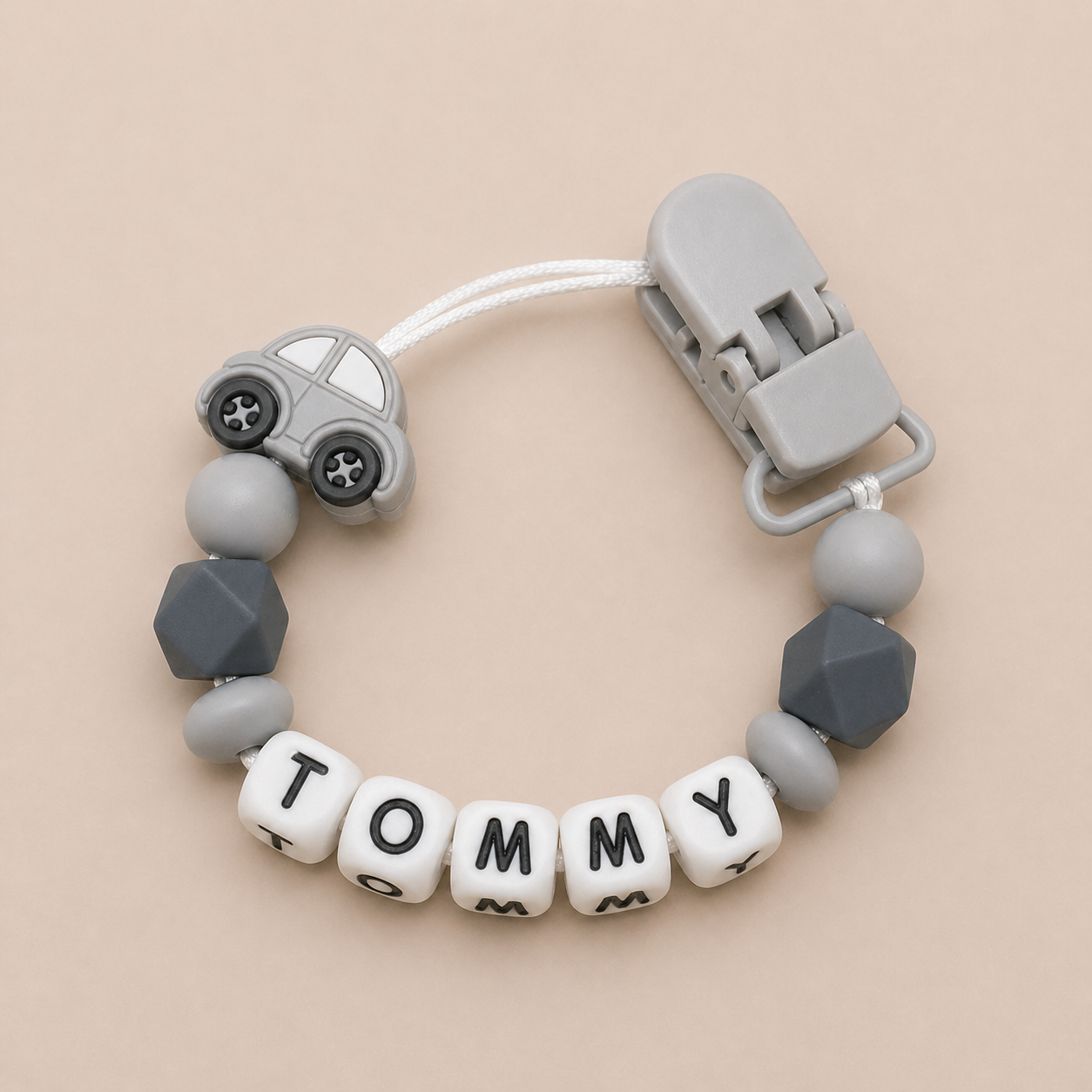 dummy clip with geometric beads and car-shaped clip on a beige background