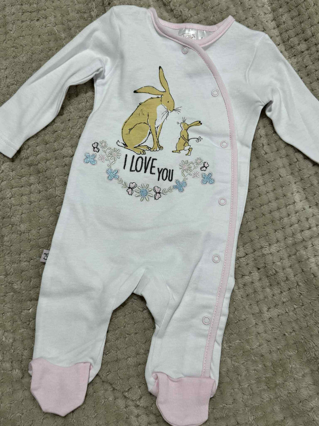 Baby onesie with bunny design and 'I love you' text on a textured surface