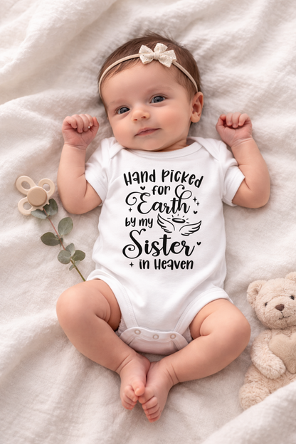 Baby wearing a onesie with text, lying on a soft surface with a teddy bear and plant.