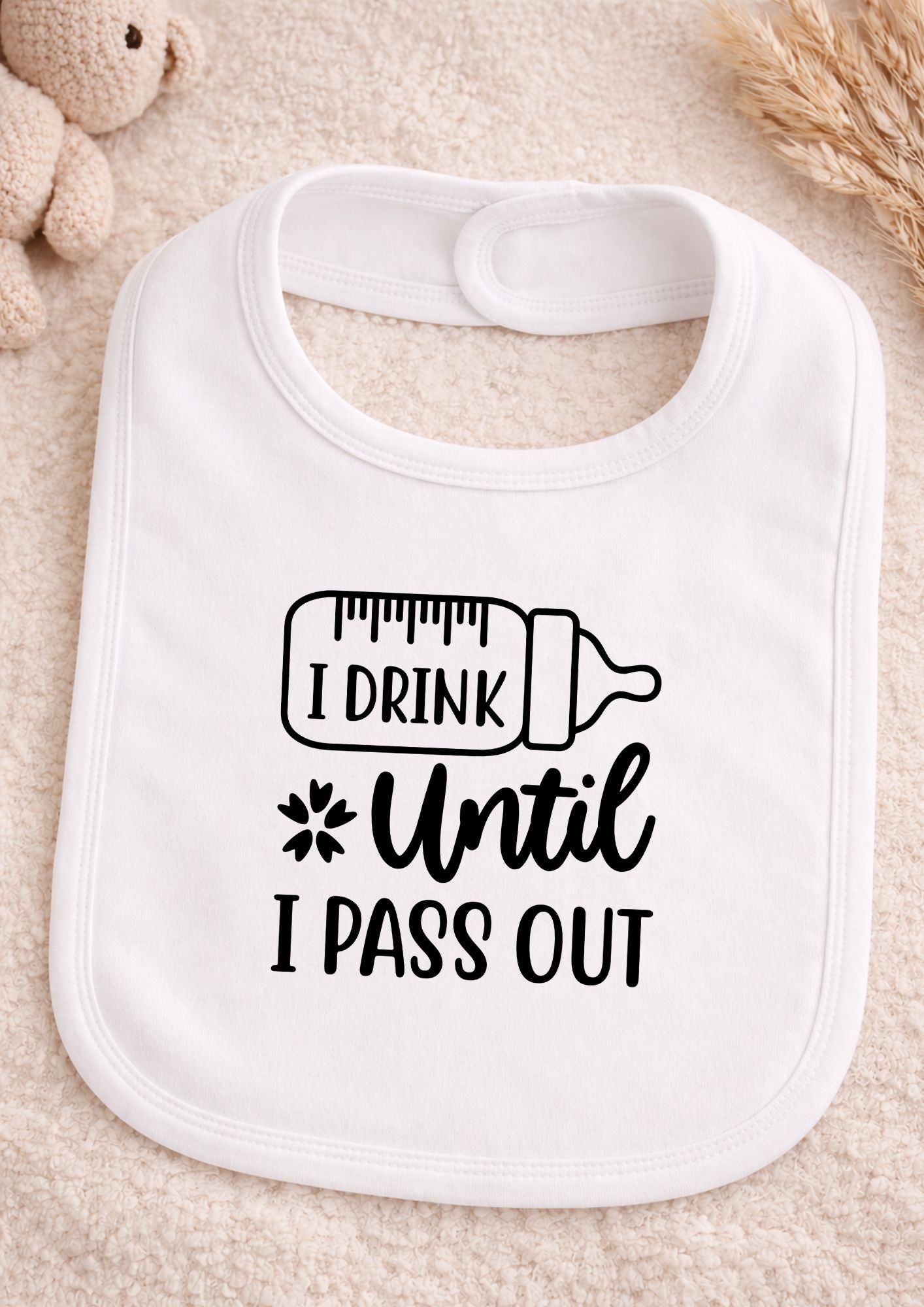 White baby bib with text 'I Drink Until I Pass Out' on a beige background
