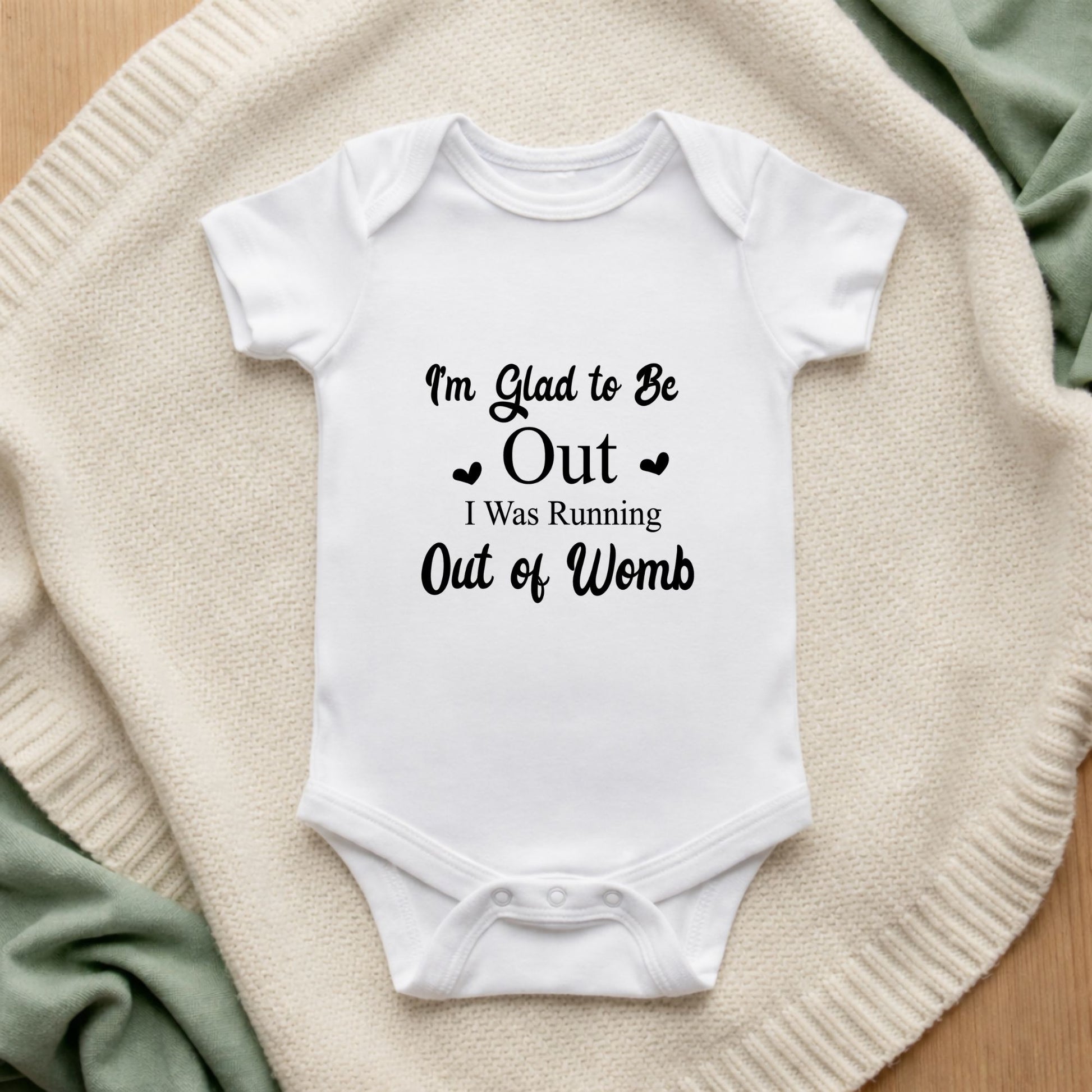 White baby onesie with humorous text on a soft surface I'm Glad to Be Out I Was Running Out of Womb Baby Bodysuit