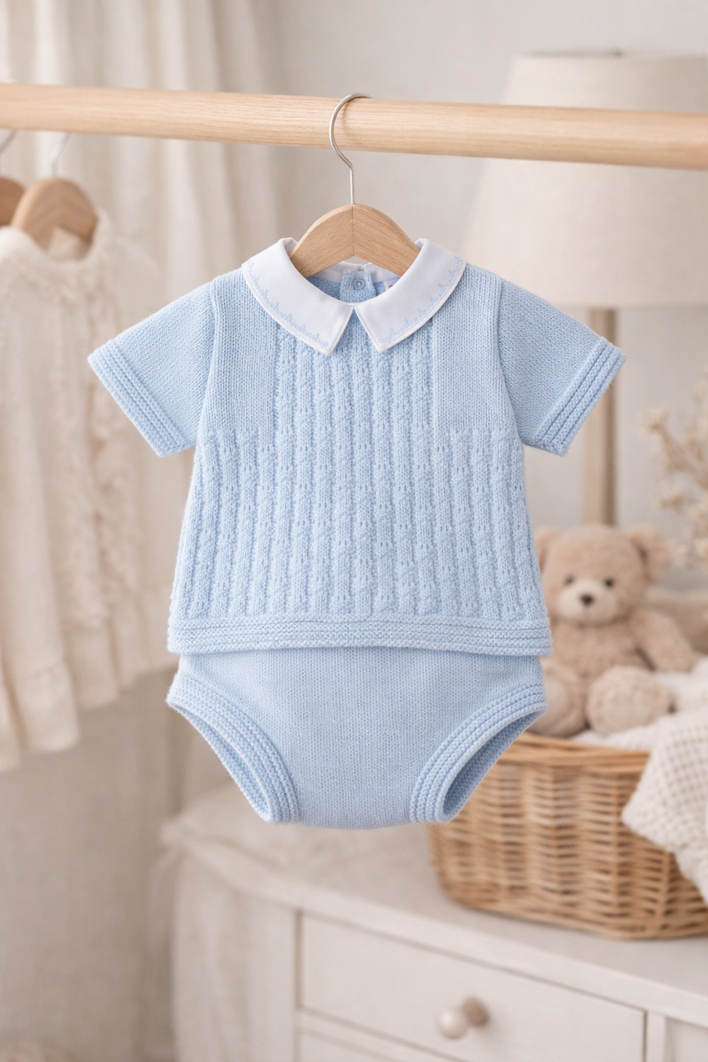 Light blue baby outfit with white collar on a hanger in a nursery setting.