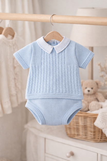 Light blue baby outfit with white collar on a hanger in a nursery setting.