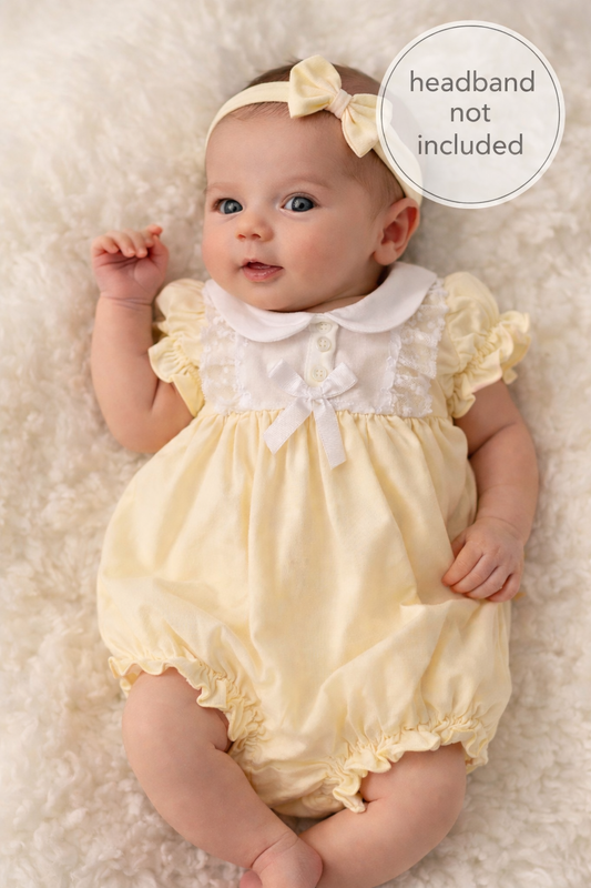 Baby in a yellow outfit with a white collar on a soft surface