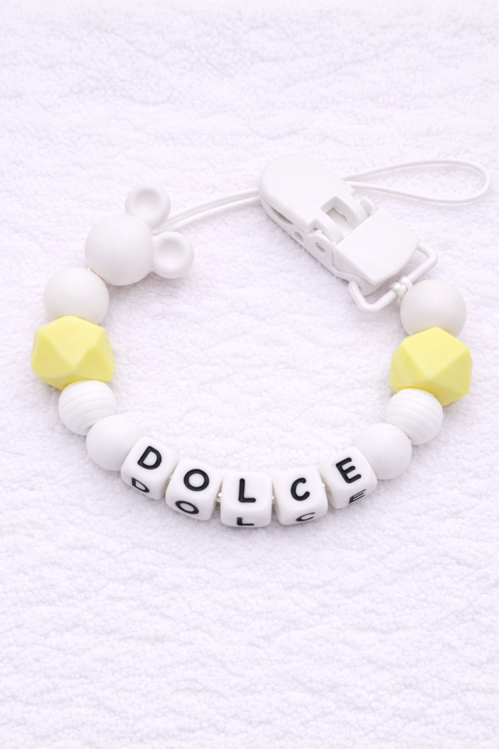 Dummy Clip with letter beads spelling 'DOLCE' on a white background