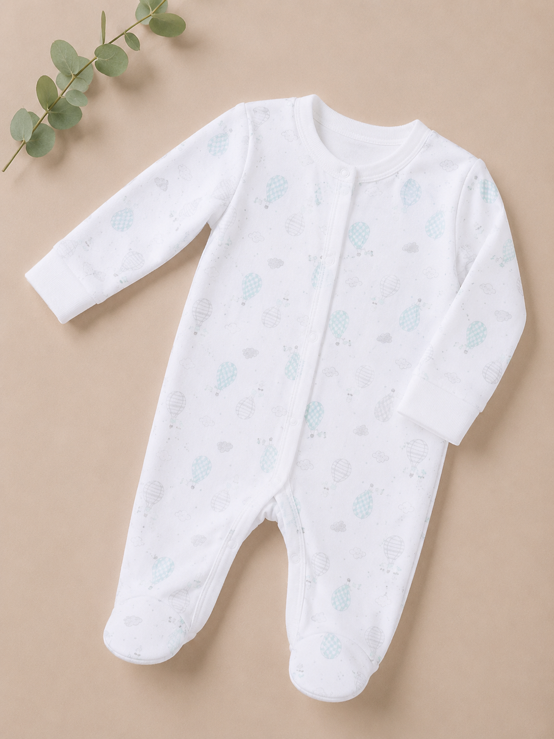 White baby onesie with blue patterns on a beige background