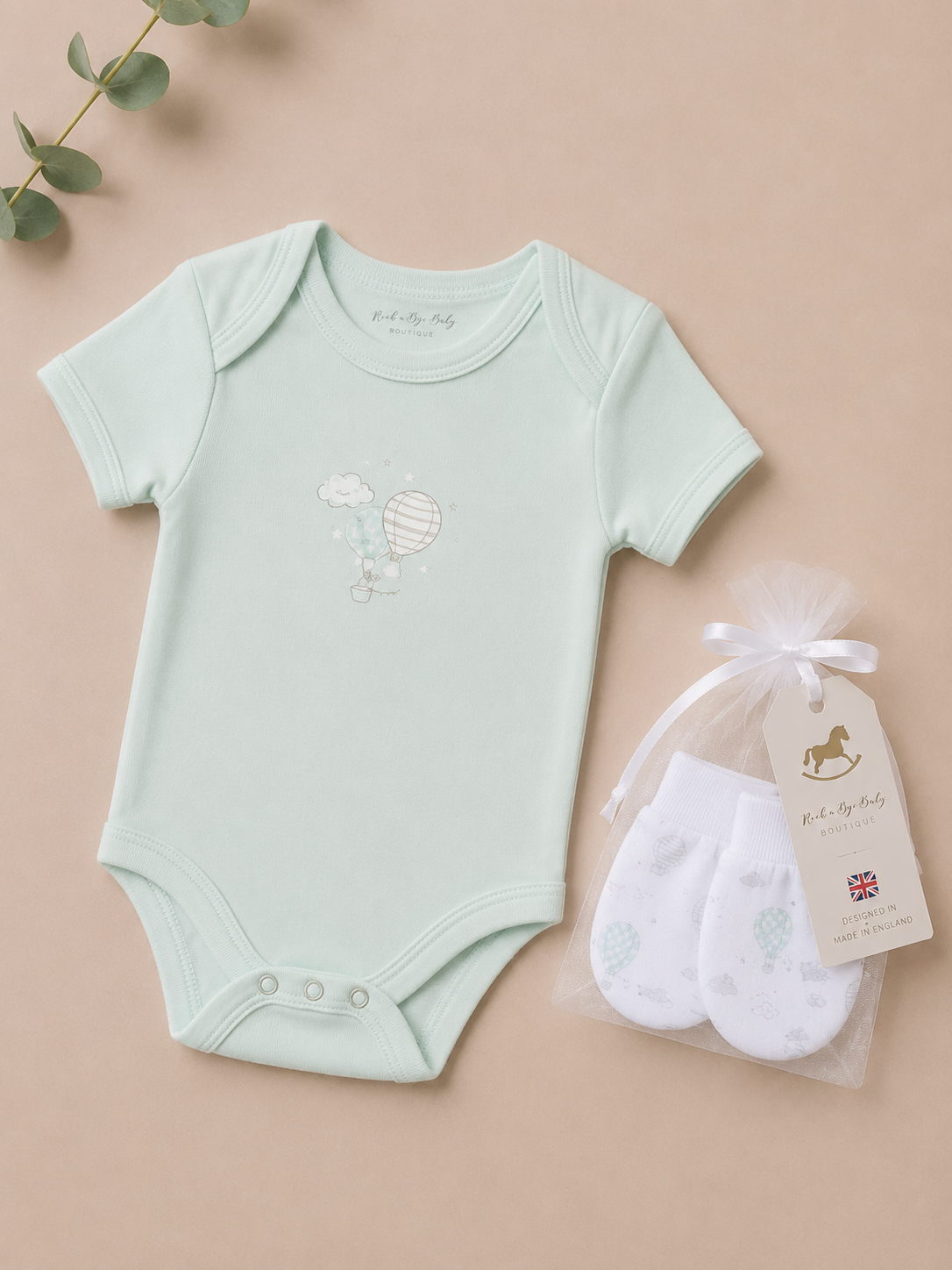 Light blue baby bodysuit with a design and white socks in a bag on a beige background