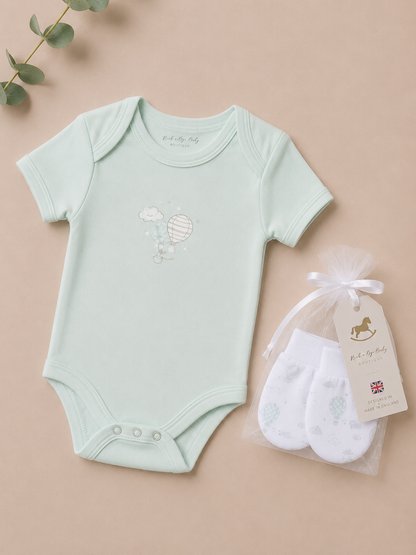 Light blue baby bodysuit with a design and white socks in a bag on a beige background
