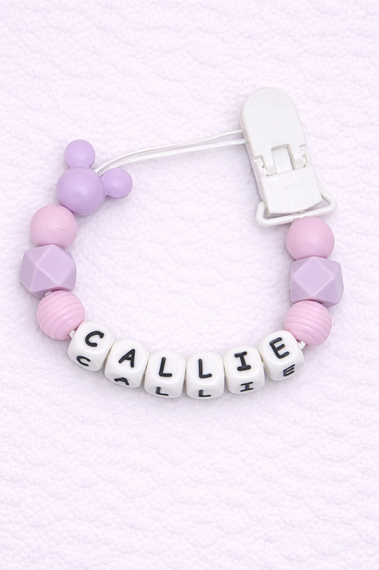 Dummy Clip with pink and purple beads and letter beads spelling 'CALLIE' on a light pink background