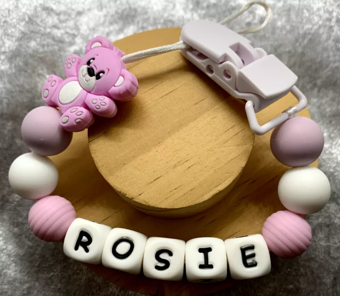 lilac/white teddybear dummy holder on a grey textured surface. Personalised with the name 'Rosie'. Change of name is available in the personalisation box. MAM Adapters are available too.